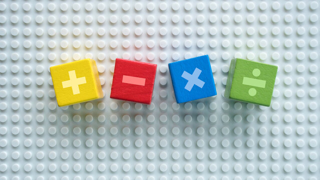 Colorful wooden blocks with math operators plus minus multiply divide on plastic baseplate background
