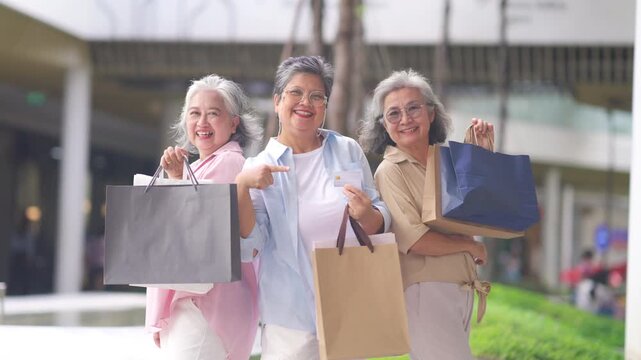 Group of Happy Asian active senior woman travel and shopping at department store in the city. Healthy elderly women friends enjoy and fun urban lifestyle holding shopping bag at shopping mall