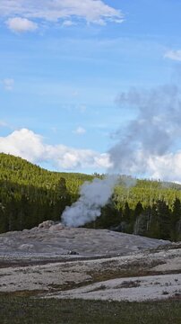 Early morning walk viewing geothermal features and hot springs in Old Faithful area of Upper Geyser Basin, summer vacation exploring Yellowstone National Park
