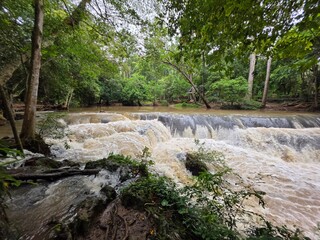 Wilderness Waterfall: A powerful waterfall cascades over rocks amidst a lush, verdant jungle, showcasing nature's raw beauty and the untamed spirit of the wilderness. © Putt_Sanplee