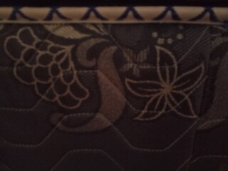 Obraz premium Dark brown floral pattern quilted fabric texture close up for background design template.