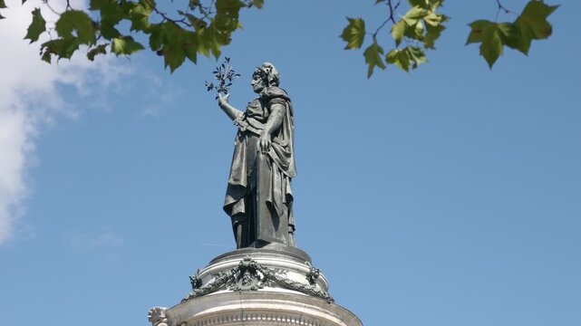 Marianne statue representing liberty and reason standing against a clear blue sky