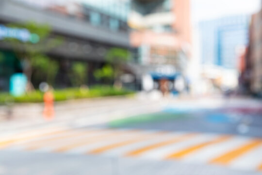 Abstract blurred modern downtown urban street background with yellow crosswalk markings and orange traffic cone