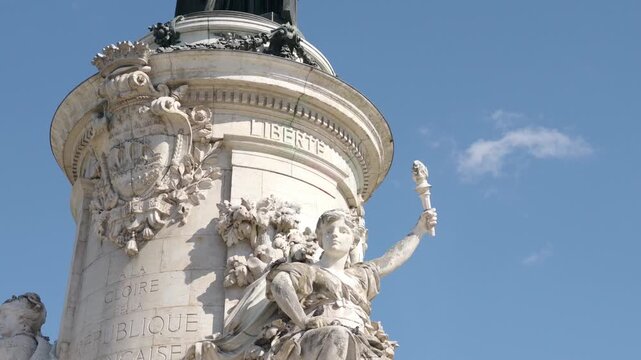 Marianne, a symbolic figure of the French Republic, holding a torch against a blue sky