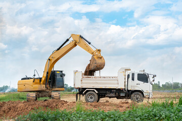 Heavy track excavator loading earth into a dumper truck for site preparation and civil engineering work. © Zblaster