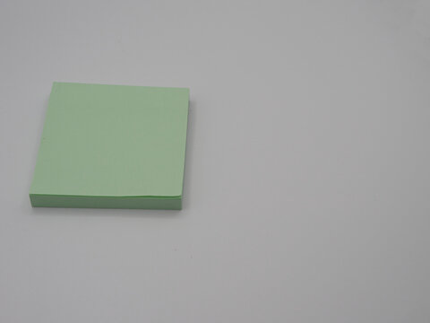 Minimal close-up of a stack of green sticky notes positioned against a neutral background, offering clean copy space for business, office, and stationery concepts.