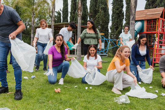 Group of diverse Latin people collecting trash in a public park in Mexico, Latin America. Group of multi age Hispanic volunteers cleaning up and collecting plastic in save the planet concept