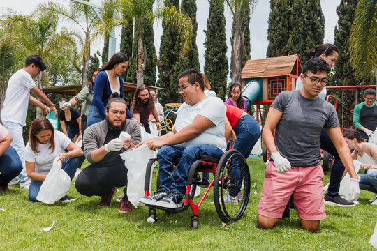 Group of diverse Latin people collecting trash in a public park in Mexico, Latin America. Group of multi age Hispanic volunteers cleaning up and collecting plastic in save the planet concept