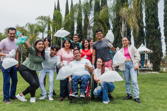 Group of diverse Latin people collecting trash in a public park in Mexico, Latin America. Group of multi age Hispanic volunteers cleaning up and collecting plastic in save the planet concept