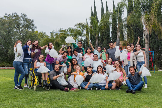 Group of diverse Latin people collecting trash in a public park in Mexico, Latin America. Group of multi age Hispanic volunteers cleaning up and collecting plastic in save the planet concept