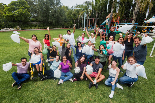 Group of diverse Latin people collecting trash in a public park in Mexico, Latin America. Group of multi age Hispanic volunteers cleaning up and collecting plastic in save the planet concept