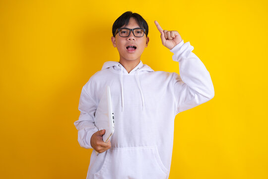 Asian Teen Boy Pointing Finger up With Excited Idea Expression Holding Laptop