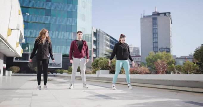 Three Friends Doing Jumping Jacks and Jogging in Place Together in the City