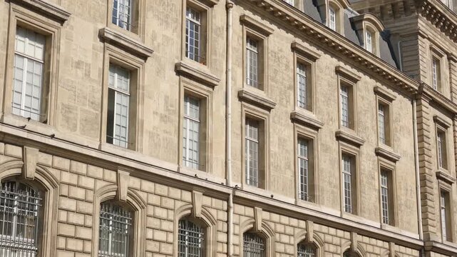 Parisian stone building facade displaying classic Haussmann architecture with multiple windows