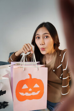 Asian woman showing Halloween shopping bags at home for online retail haul concept