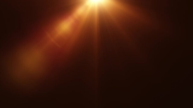 Abstract top center orange gold Shining optical lens flare light on black background. 4K seamless loop ray light beams animation. Gold light flare glowing on top on black background. Rays of light on 