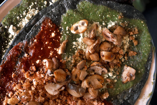 Close up of traditional Mexican blue corn handmade sopes topped with salsa, cheese and mushrooms