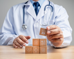 Doctor in white arranging healthcare symbol blocks to represent quality improvement, patient...