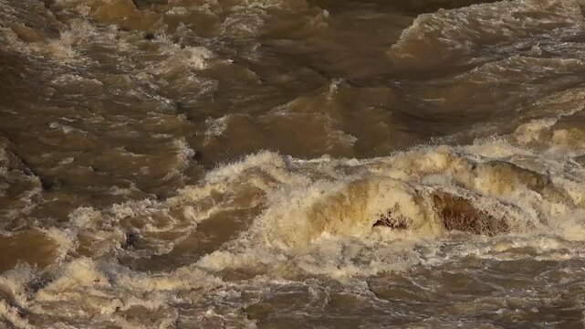 Close-up slowmotion video of the Beas River in Mandi, Himachal Pradesh, India, flowing rapidly over natural rocks after heavy monsoon rainfall.
