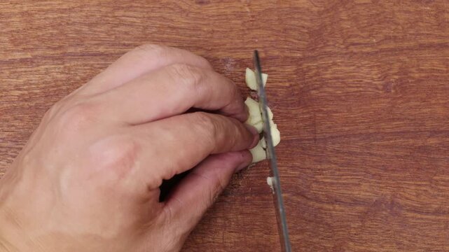 A garlic clove is crushed and finely chopped.