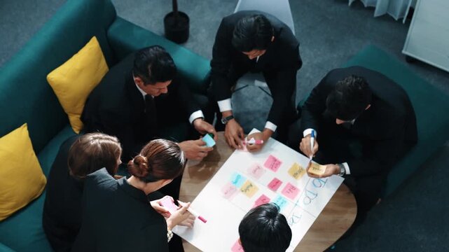 Top view of smart business team write marketing plan and putting stick notes on mind map. Group of happy business people brainstorm financial idea and planning strategy at meeting room. Directorate.