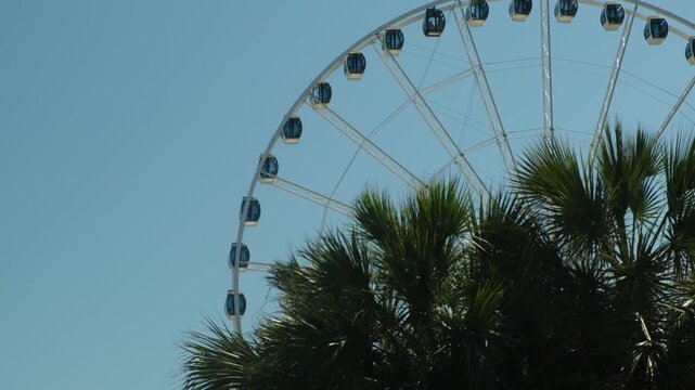 a view of a large Ferris wheel against a blue sky and darkness in the foreground