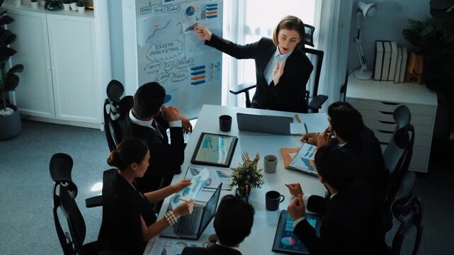 Top view of smart manager project pointing at whiteboard with mind map and financial graph and explain marketing idea while diverse investors listening and analyze stock investment chart. Directorate.