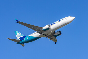 Obraz premium Toronto, Canada, September 6, 2026; WestJet Boeing 737-8 tail C-CFHCM taking off wheels up against a cloudless sky