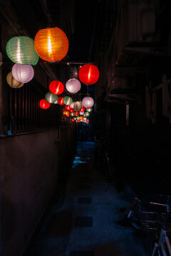 Colorful paper lanterns in a narrow Osaka izakaya alley at night