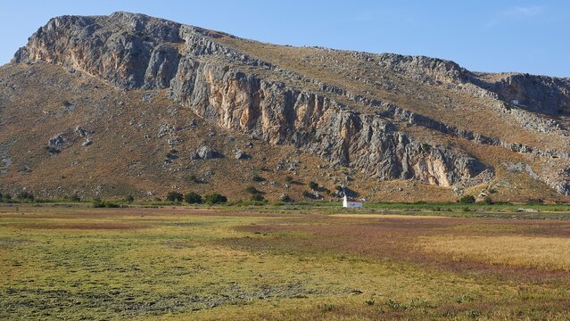 A small white chapel at the foot of a mountain surrounded by meadows, Strofilia biotope, wetlands, Kalogria, Peloponnese, Greece