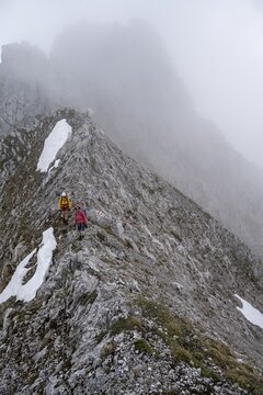 Two mountaineers with helmets in the mountains in fog, Wilder Kaiser, Kaiser Mountains, Tyrol, Austria