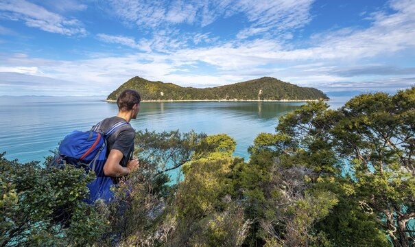 Walker overlooks Bay Astrolabe Roadstead with Adele Island, Abel Tasman National Park, Tasman, South Island, New Zealand