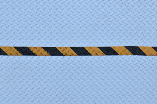 yellow black stripes hazard warning tape on light blue metal diamond plate