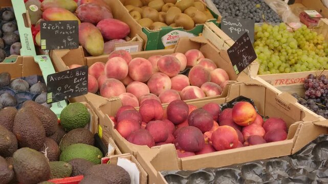 Fresh organic avocados, peaches, and nectarines displaying at a market stall in Paris