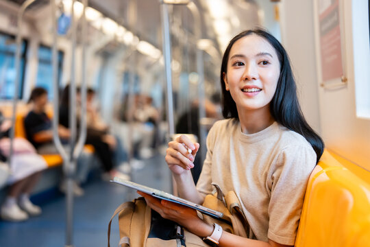 Asian young woman sitting on subway train seat while traveling in city. 