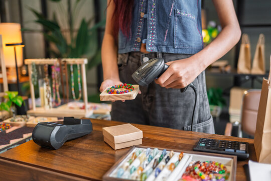Woman operating barcode scanner for handmade store checkout with digital retail technology and efficient sales management.