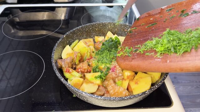 Fresh chopped parsley added to simmering meat and vegetable stew in pan.