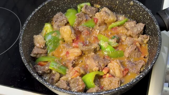 Meat and vegetables boiling in pan, close view of homemade stew cooking on stove.