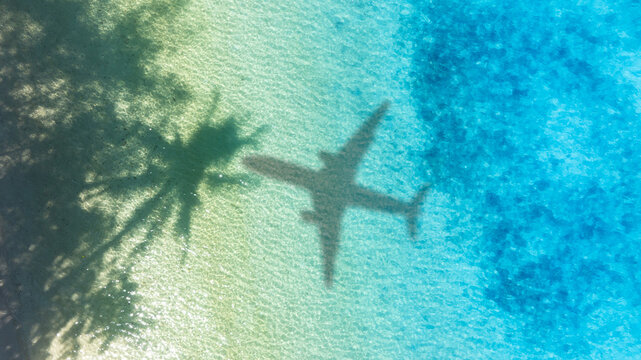 Aerial view of shadow passenger plane silhouette and sandy beach blue sea with waves at sea beach summer vacation sea travel concept	