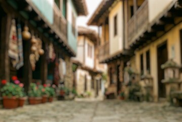 Fototapeta premium Blurred traditional village houses along a charming stone street, ideal for travel, tourism, cultural heritage, architecture, and lifestyle backgrounds.