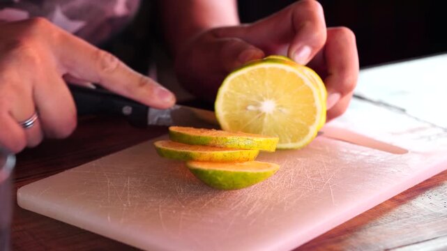 Primer plano de una persona cortando una naranja para preparar o adornar un vaso de c&oacute;ctel