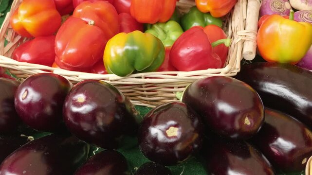 Fresh eggplants and colorful bell peppers selling at a market stall in Paris