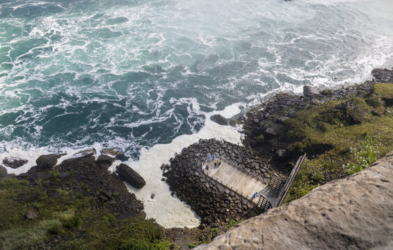 Tourists Stand on Lower Observation Deck Overlooking Rushing Niagara Falls Waters