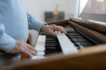 Close up of hand of elderly person play organ keyboard instrument making music with peaceful focused emotion in comfortable home © Ratirat