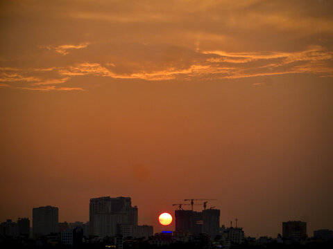 Fiery Orange Sunset Above Silhouetted City Skyline and Cranes on West Lake in Hanoi, Vietnam