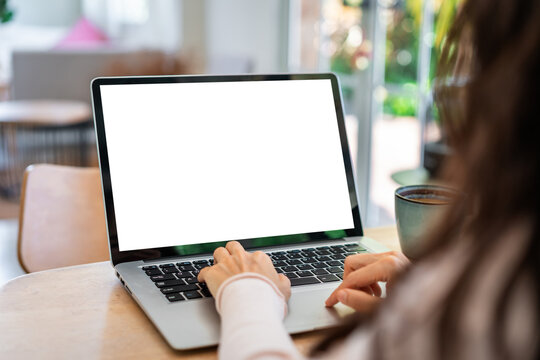 Freelancer working online: Over the shoulder shot of a woman using laptop computer with empty copy space display screen in bright home office
