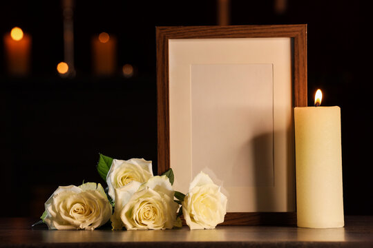 Funeral memorial and sympathy tribute, blank wooden photo frame with white roses and burning candle for bereavement and remembrance ceremony