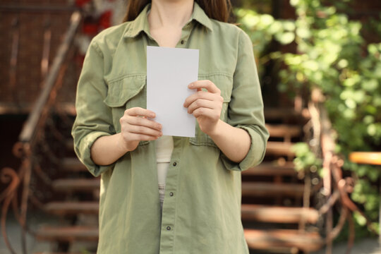 Marketing and advertising mockup, woman holding blank white flyer for brand promotion and corporate communication in outdoor urban environment