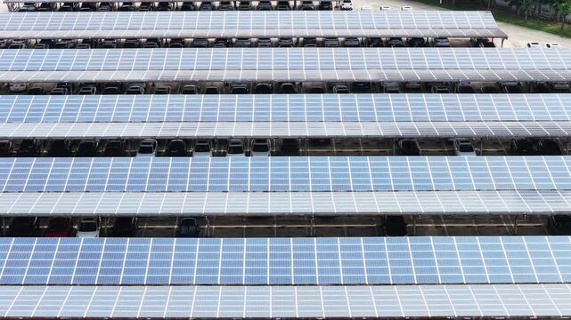 Approaching aerial view of solar panels above parked cars