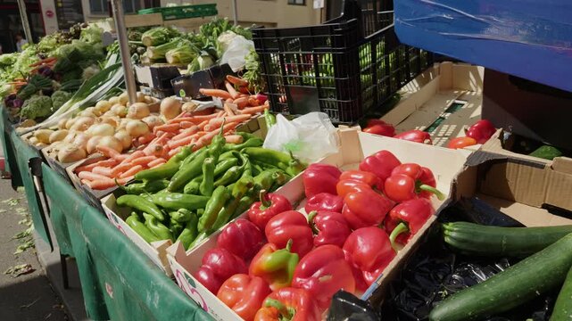Fresh vegetables like peppers, carrots, and onions displayed for sale at a vibrant outdoor market